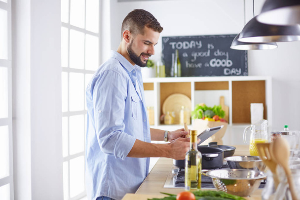 Chef sonriente y seguro de sí mismo de pie en gran cocina - Foto, imagen