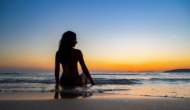 Silhouette of a woman on the beach at sunset - Valokuva, kuva