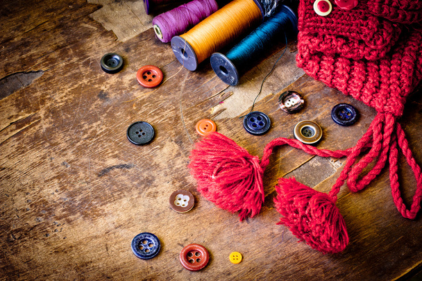 Set of spools of threads vintage buttons with knitted cap on old wooden table - Фото, зображення