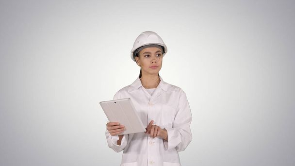 Woman engineer checking information and objects on her tablet on gradient background. - Foto, Imagem