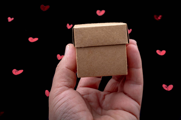 Caja de cartón de mano sobre fondo con corazones
 - Foto, imagen
