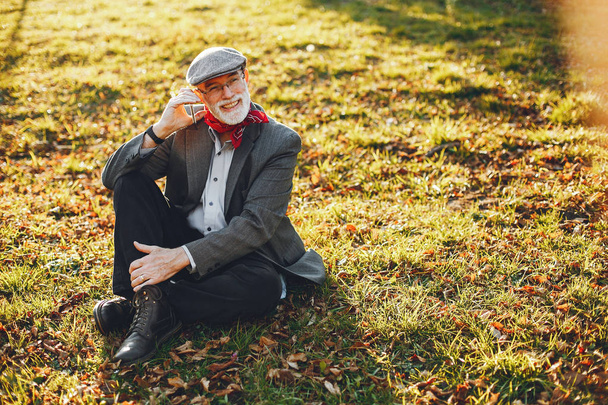 Elegant old man in a sunny autumn park  - Fotó, kép