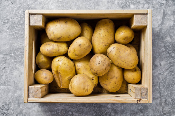 Pommes de terre dans une boîte en bois, supermarché. Fond gris, vue de dessus, gros plan
 - Photo, image