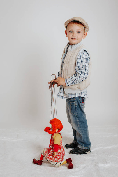 Μικρό αγόρι στο καπάκι στέκεται με μια κούκλα κουκλοθέατρου - Φωτογραφία, εικόνα