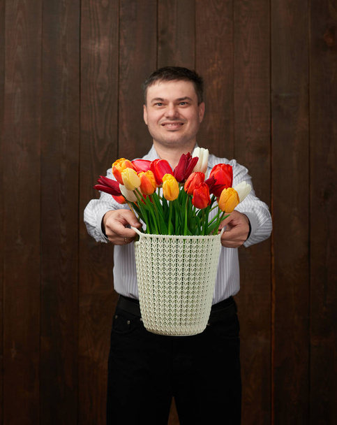 El hombre sostiene una cesta con flores
 - Foto, imagen
