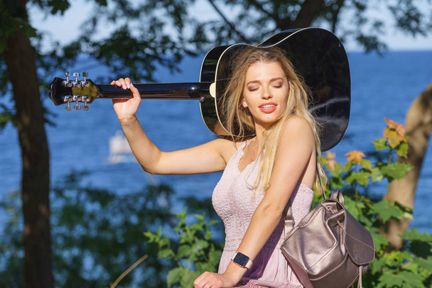 Woman playing acoustic guitar in park - Фото, зображення