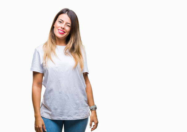 Mladá krásná žena příležitostné bílé tričko přes samostatný pozadí mrkání, při pohledu na fotoaparát se sexy výraz, veselý a šťastný obličej. - Fotografie, Obrázek
