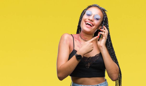 Young braided hair african american with birth mark talking on smartphone over isolated background very happy pointing with hand and finger - Fotoğraf, Görsel