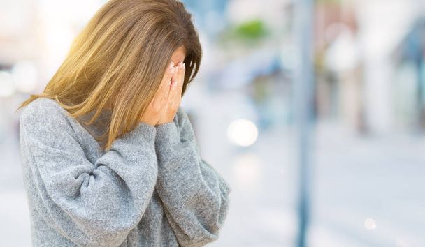 Красивая женщина средних лет в зимнем свитере на изолированном фоне с грустным лицом, покрывающим лицо руками во время плача. Концепция депрессии
. - Фото, изображение