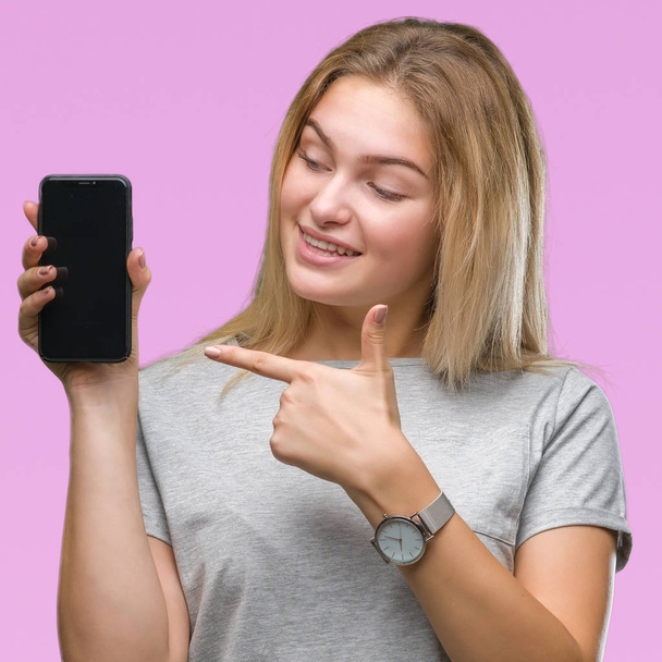 Young caucasian woman showing screen of smartphone over isolated background very happy pointing with hand and finger - Foto, afbeelding