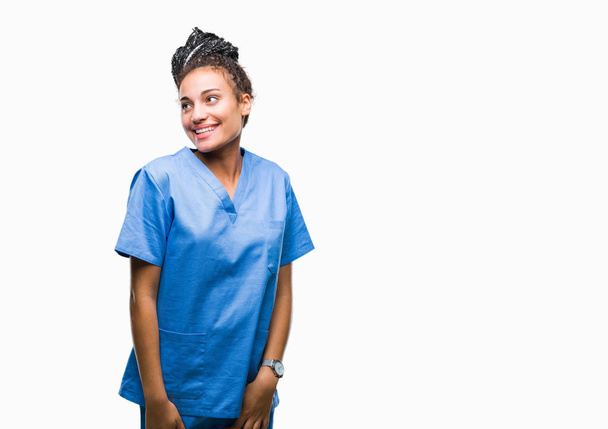 編んだ髪の若いアフリカ系アメリカ人女の子専門看護師は、背景の自然な表現の顔に笑みを浮かべて側に離れて見てを隔離しました。自信を持って笑ってください。. - 写真・画像