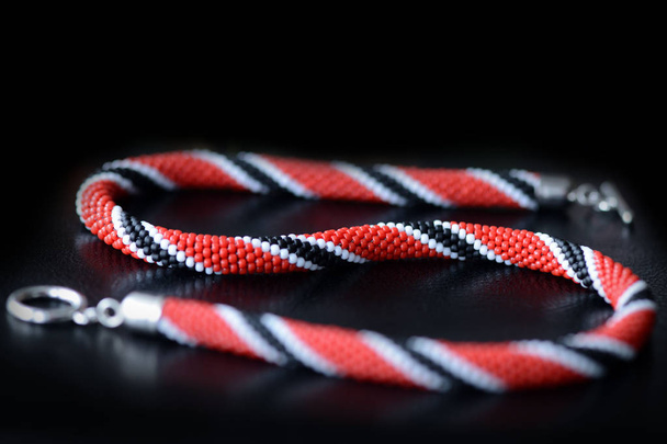 Bead crochet necklace red, black and white colors on a dark background close up - Foto, Imagem