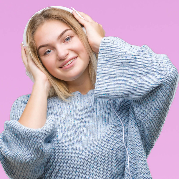 Молодая белая женщина слушает музыку в наушниках на изолированном фоне со счастливой и прохладной улыбкой на лице. Счастливчик
. - Фото, изображение