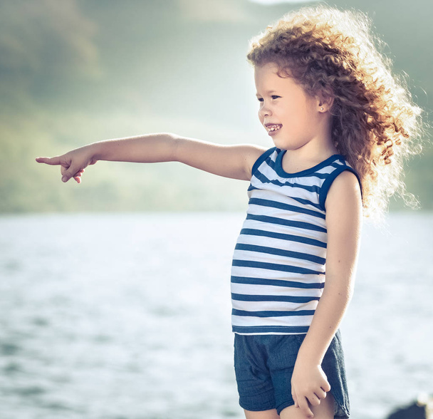 Little girl pointing near the sea - Фото, изображение