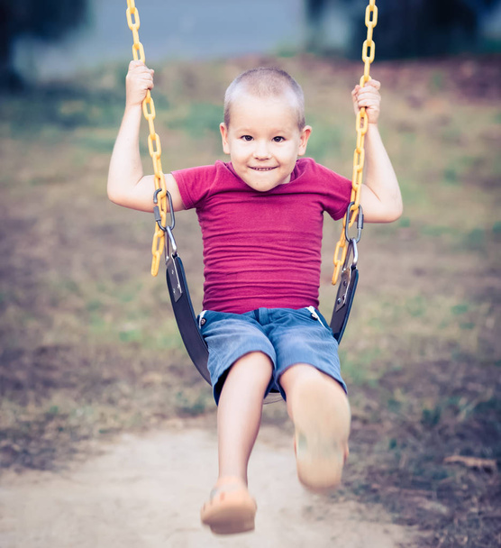 Little boy swinging on a swing - Fotó, kép