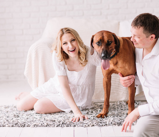 young family with their dog sitting on the bed in the bedroom - Photo, Image