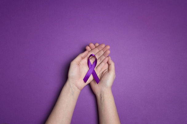 Hands holding Purple ribbons on a purple background. World epile - Valokuva, kuva