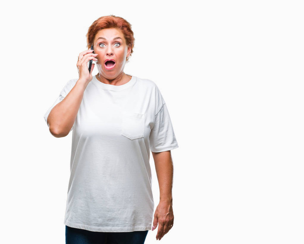 Atrractive vanhempi valkoihoinen punapää nainen puhuu älypuhelimella yli eristetty tausta peloissaan shokissa yllätys kasvot, peloissaan ja innoissaan pelko ilme
 - Valokuva, kuva