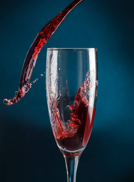 splash in a champagne glass from falling red wine on a dark blue background - Valokuva, kuva