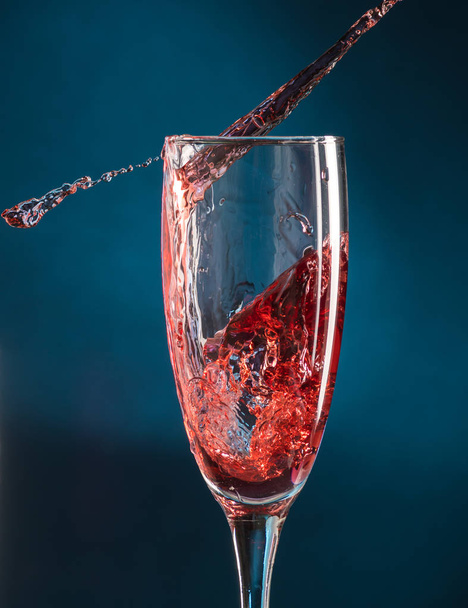 splash in a champagne glass from falling red wine on a dark blue background - Foto, Imagem
