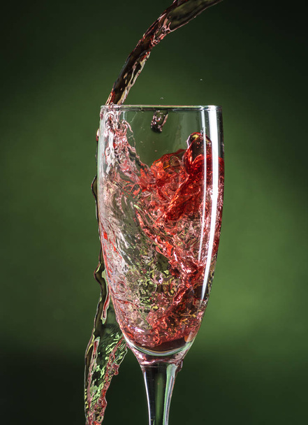 splash in wine glass from falling red wine on a dark green background - Φωτογραφία, εικόνα