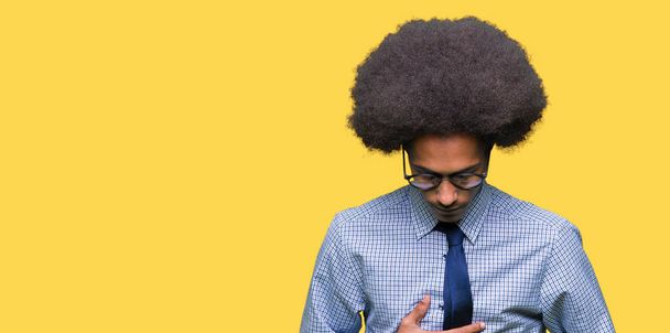 junger afrikanisch-amerikanischer Geschäftsmann mit Afro-Haaren, der eine Brille mit der Hand auf dem Bauch trägt, weil Verdauungsstörungen, schmerzhafte Krankheit sich unwohl fühlen. Schmerzkonzept. - Foto, Bild