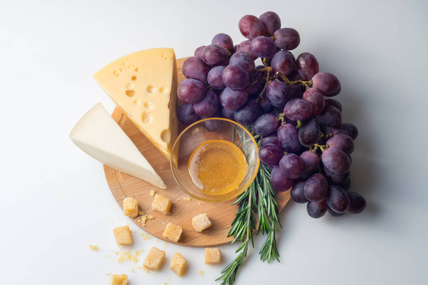 Cheese selection, honey and grape isolated on white background - 写真・画像