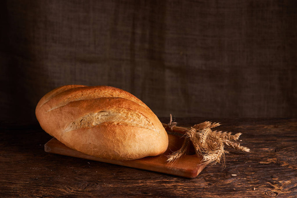 Αρτοποιείο - χρυσό ρουστίκ κακότροπος καρβέλια ψωμί και ψωμάκια σε φόντο μαύρο πίνακα κιμωλίας. Still life συλλαμβάνονται από ψηλά - Φωτογραφία, εικόνα