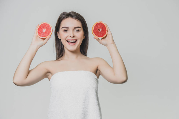 Beauty portrait of a beautiful healthy young topless woman with long red hair showing sliced grapefruit. - Foto, immagini