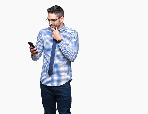 Giovane uomo d'affari utilizzando smartphone su sfondo isolato volto serio pensando alla domanda, idea molto confusa
 - Foto, immagini