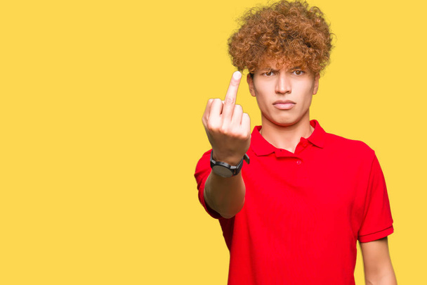 Young handsome man with afro hair wearing red t-shirt Showing middle finger, impolite and rude fuck off expression - Photo, Image