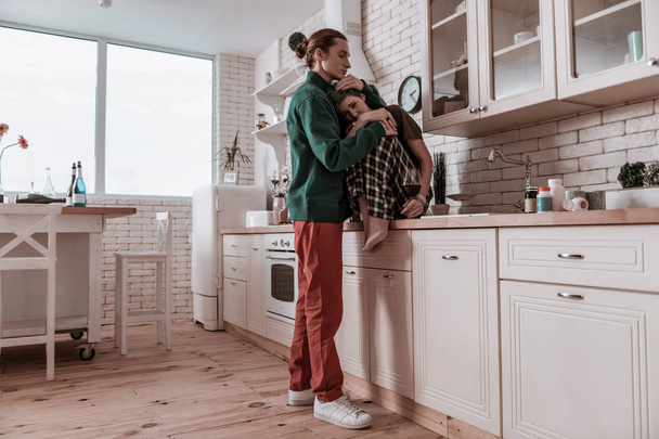 Boyfriend wearing red trousers hugging his tender little girl - Fotografie, Obrázek