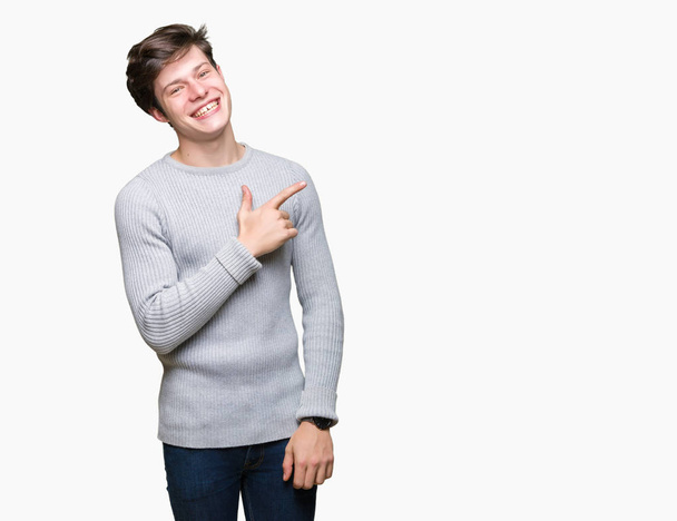 Nuori komea mies yllään talvi villapaita yli eristetty tausta iloinen hymy kasvojen osoittaa käsi ja sormi jopa puolelle onnellinen ja luonnollinen ilme kasvot
 - Valokuva, kuva