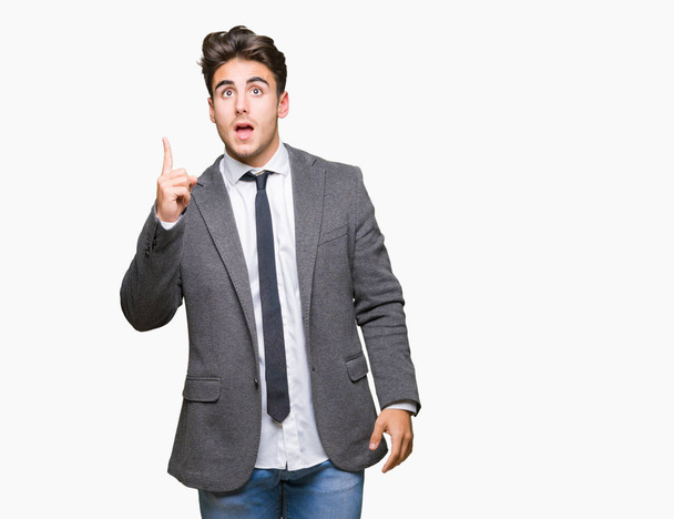 Young business man wearing suit and tie over isolated background pointing finger up with successful idea. Exited and happy. Number one. - Photo, Image