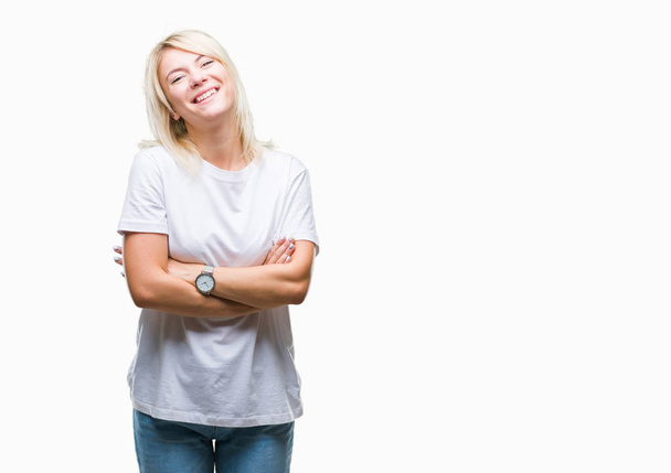 Young beautiful blonde woman wearing white t-shirt over isolated background happy face smiling with crossed arms looking at the camera. Positive person. - Foto, Imagen