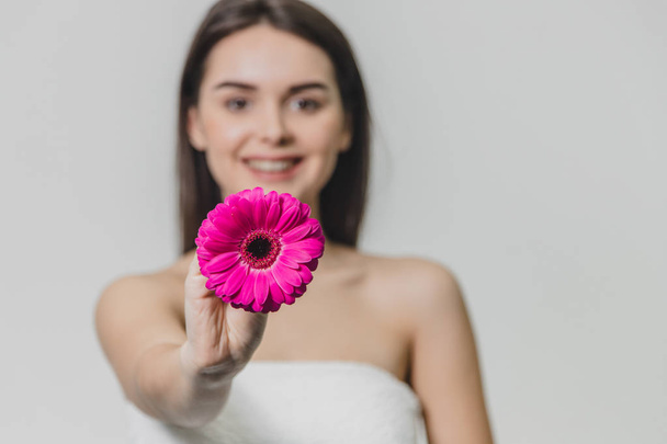 Young beautiful girl on a white background. Close-up of a girl holding a flower on her arms outstretched. - Foto, afbeelding