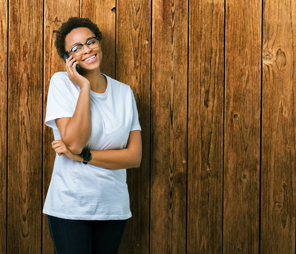 Młody african american kobieta rozmawia przez telefon na białym tle z szczęśliwy twarz stałego i uśmiechając się z uśmiechem pewnie Wyświetlono zębów - Zdjęcie, obraz