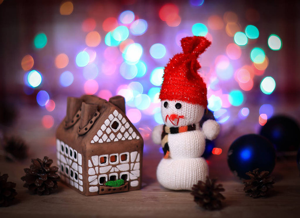 toy snowman and gingerbread house at the Christmas table - Фото, зображення