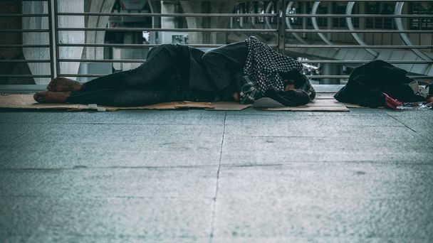 Povero senzatetto o rifugiato che dorme sul pavimento della strada pubblica in città
. - Foto, immagini