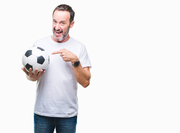 Middle age hoary senior man holding soccer football ball over isolated background very happy pointing with hand and finger - Fotó, kép