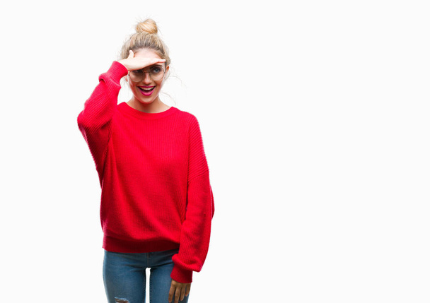 Fiatal gyönyörű szőke nő visel piros pulóver és a szemüveget, mint elszigetelt háttér nagyon boldog és mosolyog néz messze kéz alatt a fej. Keres a koncepció. - Fotó, kép