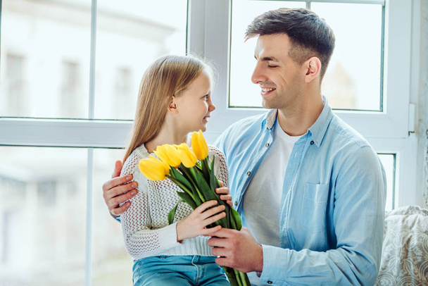 Time with dad is always great.Father gives her daughter a bouquet of tulips. - Foto, immagini