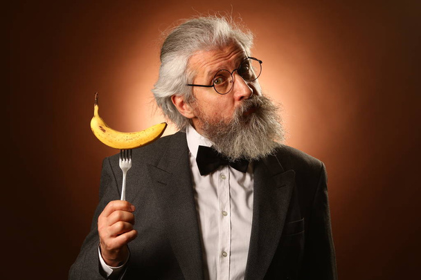 Portrait of a gray-haired elderly gentleman, with a shaggy mustache and beard, in a white shirt and gray jacket, wearing glasses and a fork - Photo, Image