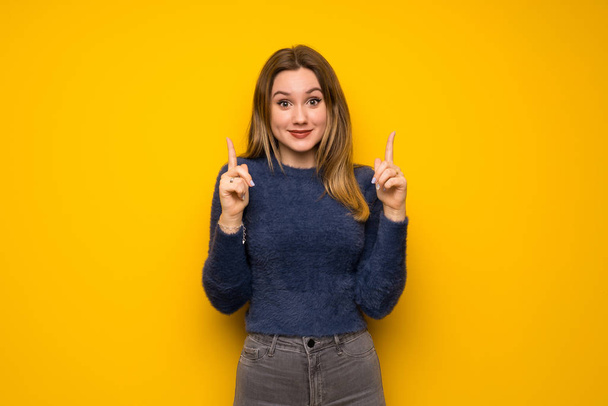 Tiener meisje over gele muur wijzen met de wijsvinger een geweldig idee - Foto, afbeelding