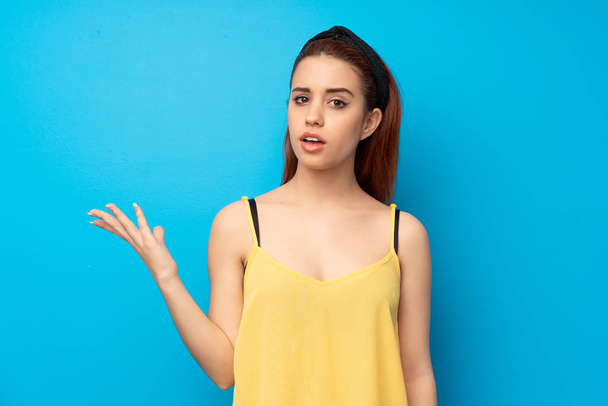 Young redhead woman over blue background making doubts gesture - Photo, Image