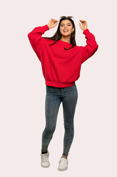 Un plan complet d'une adolescente avec un pull rouge avec des lunettes et souriant sur fond isolé
 - Photo, image