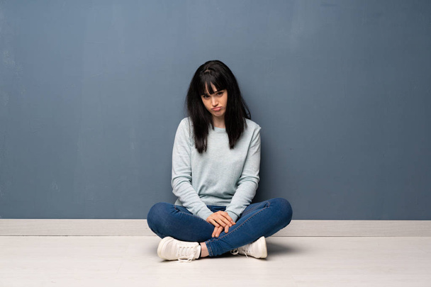 Γυναίκα που κάθεται στο πάτωμα με λυπημένος και καταθλιπτικός έκφραση - Φωτογραφία, εικόνα