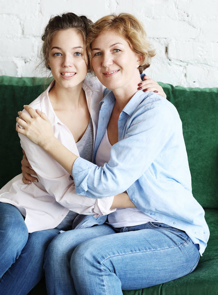 Beautiful senior mom and her adult daughter are hugging, looking at camera and smiling - Foto, afbeelding