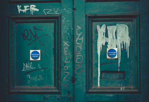 A light blue abandoned fire door with graffiti painted over it. - Photo, Image