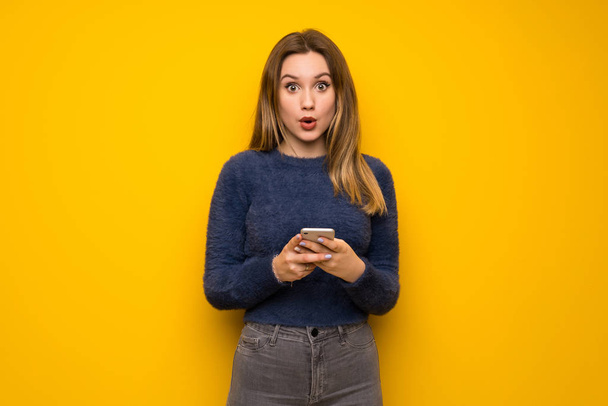 Nastolatek dziewczyna nad żółte ściany, zaskoczony i wysyłanie wiadomości - Zdjęcie, obraz
